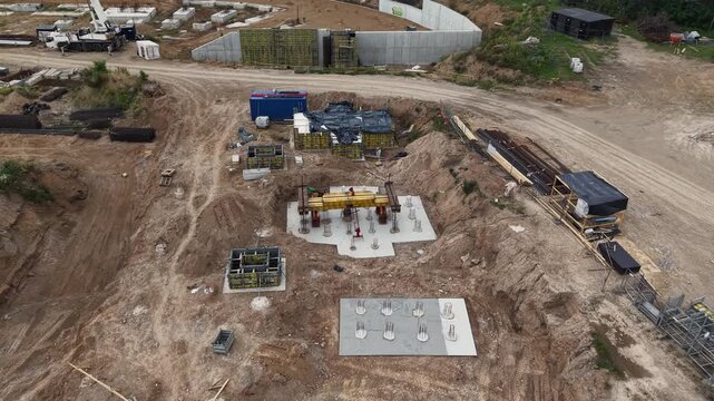 Drone close-up of Vilnius National Stadium construction with concrete foundation pads, rebar formwork, anchor bolts and excavation earthworks on a major infrastructure site - 16 August 2025