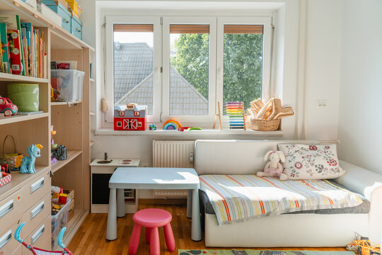 Tidy children room. Interior decor of clean children's room. Organizing storage in kids room: bookshelves and educational and soft toys. Montessori education. A childs bedroom with toys and books.