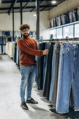 Stylish man shopping for denim jeans in clothing store