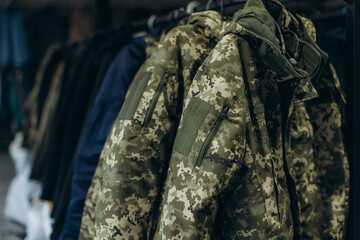 Camouflage military jacket with digital pattern hanging on rack
