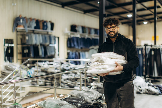 Retail worker holding clothes in clothing store warehouse - Powered by Adobe