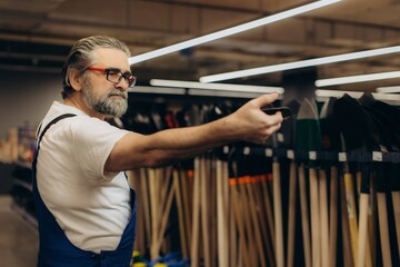 Senior man shopping for gardening tools in hardware store