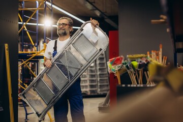 Mature man carrying ladder in hardware store © Roman