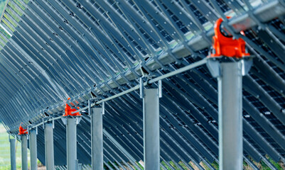 Naklejka premium Close-up of industrial solar panels with steel structures and orange fixtures