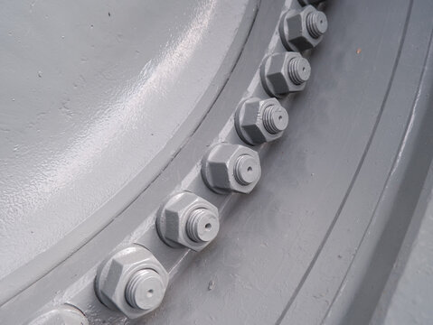 industrial heavy-duty wheel rim with large steel bolts and nuts. Grey painted metal flange for trucks or construction machinery detail