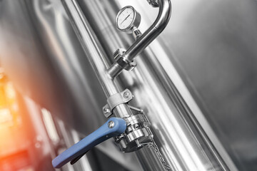 Industrial beer brewing equipment with stainless steel tanks and pressure gauge