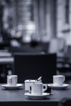 tazze da caff&egrave; su dei piatti in primo piano, con ambiente urbano sullo sfondo sfuocato, di giorno 