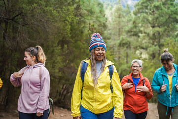 Multiracial women having fun during trekking day into the wood - Escape to the nature and travel...