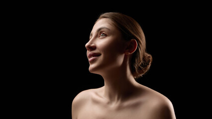 Dramatic low key female portrait on black background with soft highlights. Concept of media influence, idealized beauty, visual narratives, and modern advertising culture.