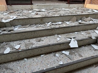 Damaged concrete stairs covered with broken ceiling fragments and debris, showing unsafe...
