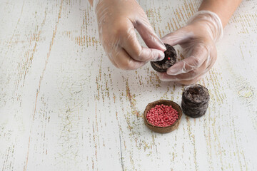 A woman wearing gloves plants a carrot seed in a soaked peat pellet to grow seedlings. Planting vegetable and flower seeds