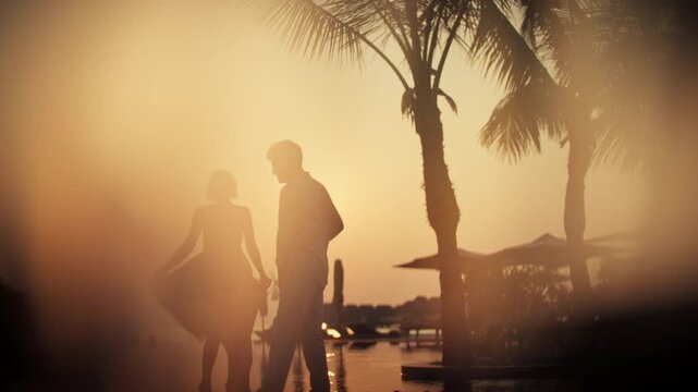 Honeymoon couple enjoying cocktails at a tropical sunset by the resort pool