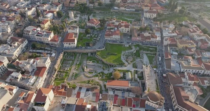 Cinematic drone flight over Hadrian&rsquo;s Library and the Roman Forum of Athens at sunset. Ancient ruins glow in warm golden light, revealing historic architecture and timeless atmosphere ideal for travel