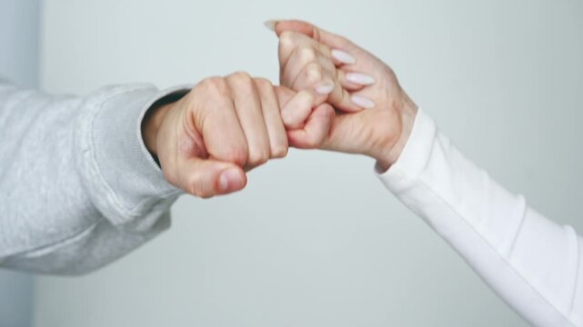 Two people making up after a fight.
A gesture of reconciliation and resentment.
Kindness and friendship.
People holding each other's pinkies.
Two pinkies