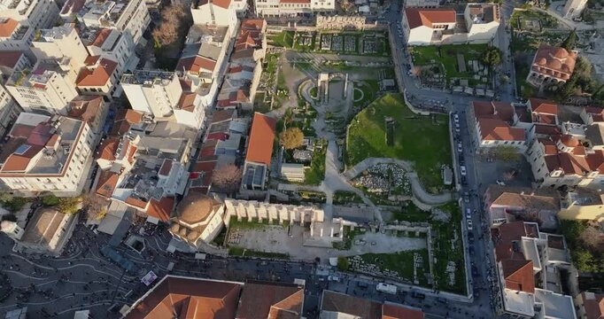 Cinematic revealing drone shot of Hadrian&rsquo;s Library in Athens, Greece at sunset. Ancient stone ruins glow in warm golden light, creating a dramatic historic atmosphere ideal for travel and culture pr.
