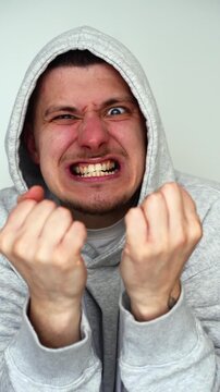 A guy's angry expression against a white background.
The man is angry and baring his teeth in frustration.
The man is displaying negative emotions and shaking with anger.
