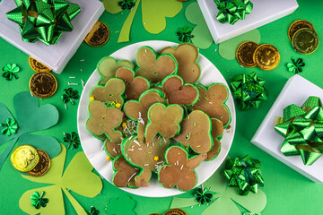Shamrock shaped green tasty sweet pancakes for St Patricks day breakfast. Creative homemade tasty fried pan cakes with sugar sprinkles and Saint Patrick holiday decor