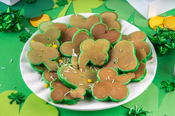 Shamrock shaped green tasty sweet pancakes for St Patricks day breakfast. Creative homemade tasty fried pan cakes with sugar sprinkles and Saint Patrick holiday decor