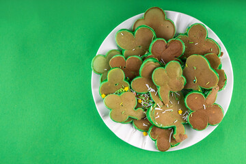 Shamrock shaped green tasty sweet pancakes for St Patricks day breakfast. Creative homemade tasty fried pan cakes with sugar sprinkles and Saint Patrick holiday decor