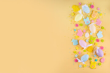 Cute and bright pastel colored Easter eggs and bunny background. Pink. blue, yellow colored bunny rabbits, eggs and flowers sugar sprinkles on light yellow background