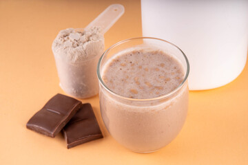 Chocolate collagen powder and drink on beige background, Plastic jar mock-up with chocolate collagen powder, portion scoop and glass with cocoa collagen drink with pieces of chocolate