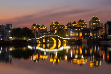 Fototapeta premium Stone arch bridge and city modern architecture night view at Jinji Lake, Suzhou, China