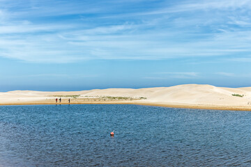 Three fishermen walking around lagoon formed by sand dunes at the closed mouth of the Gamtoos river...