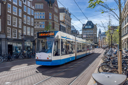 Amsterdam tram route 2 to Centraal Station with bicycles and Dutch architecture in daylight. AMSTERDAM, NETHERLANDS - APRIL 10 2024