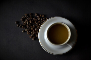 Top view of cappuccino and coffee beans on a dark background.