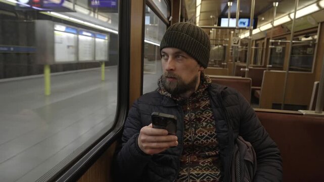 Passenger browsing internet on his phone inside a classic Munich underground wagon. Historic vintage subway train moving through a station. Morning commute in Muenchen, Germany.