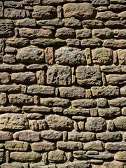 Obraz premium Aged stone wall background with irregular pattern under natural light