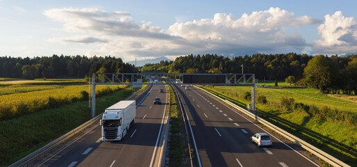 Trucks travel on a highway surrounded by fields, driving goods for e-commerce and supporting logistics networks.
