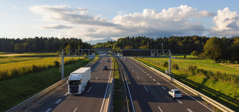 Trucks travel on a highway surrounded by fields, driving goods for e-commerce and supporting logistics networks.