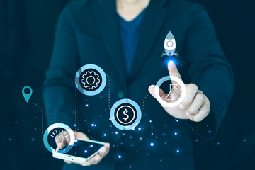 Financial growth concept: Hand touching a rocket launch icon on a futuristic interface. Symbols of money, strategy, and innovation represent business success