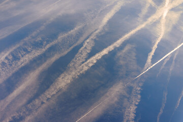 Clouds in the sky reveal trails left by planes flying high above. The clear blue background highlights the lines formed by the planes paths.