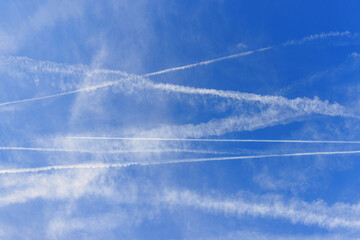 White trails streak across the blue sky where planes have passed. The scene shows various patterns formed by the contrails above.