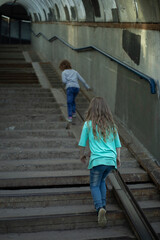 Children walking on an overhead pedestrian crossing. Kids in town. Girls climbing stairs.