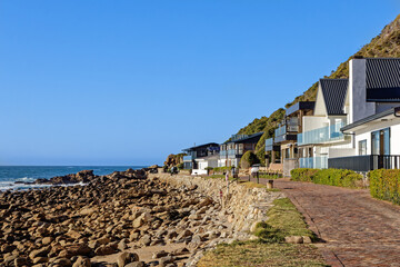 Luxury holiday homes along a rocky shoreline at Victoria Bay in the Western Cape, South Africa