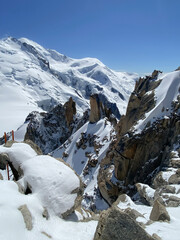 Snow covered alpine mountain landscape with rocky peaks and blue sky