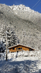 Snowy alpine mountain landscape with wooden chalet and winter forest