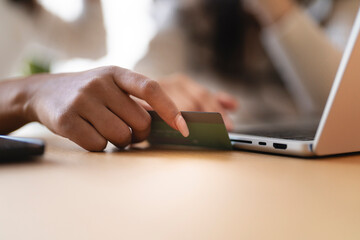 A person's hand inserts a credit card into a laptop, signifying online shopping or payment.