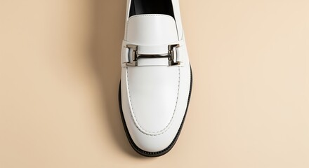 White leather loafer with silver metal buckle detail on beige background. Perfect for fashion catalogs, footwear advertisements, luxury brand campaigns, or product showcases.
