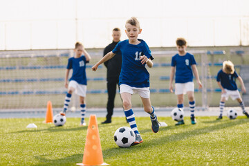 Boys attending soccer training on school field. Young man coaching children on physical education class. Soccer practice for children