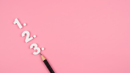 White 3D numbers 1, 2, and 3 with a black pencil pointing to the number three on a bright pink background, top view