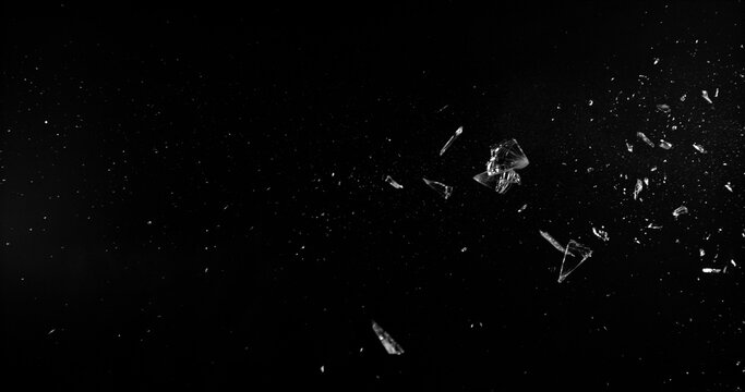 Side angle photo of flying shattered glass shards and dust isolated on black background. High detail debris explosion, perfect for VFX overlay, compositing, transitions or dramatic design elements.