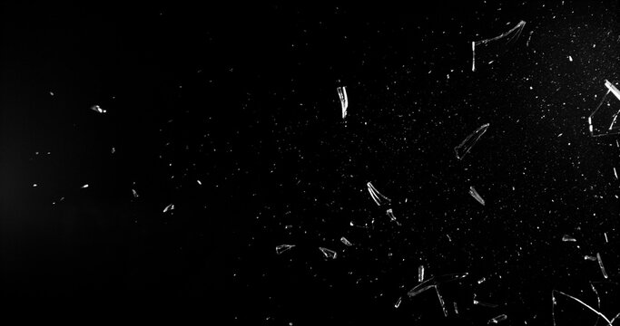 Side angle photo of flying shattered glass shards and dust isolated on black background. High detail debris explosion, perfect for VFX overlay, compositing, transitions or dramatic design elements.