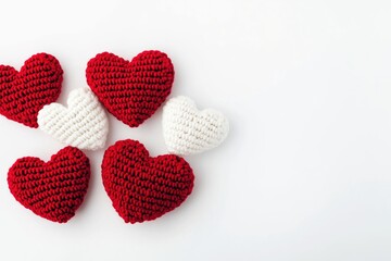 Fototapeta premium Crocheted red and white hearts arranged on a white background, representing romance, affection, and handmade crafts for celebratory occasions