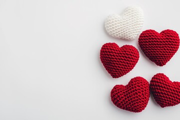 Fototapeta premium Knitted red and white hearts arranged on a white background, symbolizing love, romance, and celebration