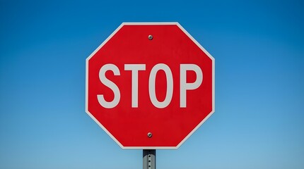 Obraz premium “STOP” sign in bold and highly visible white colored, designed to immediately catch attention. This sign is commonly found at road intersections to control traffic flow.