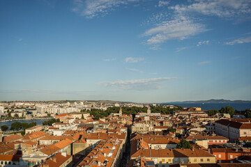 Obraz premium High viewpoint panoramic view of Zadar old town with red tiled roofs and Adriatic Sea seen from the bell tower. Travel destination cityscape with historic architecture and coastal horizon. 